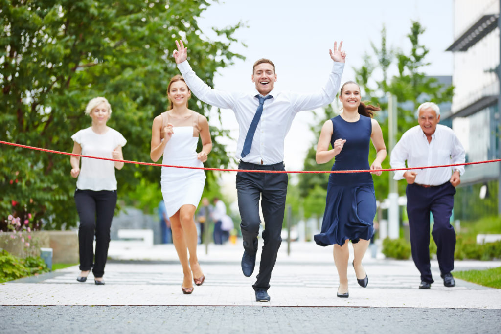 Business man is the winner while running with a business team to the finish line